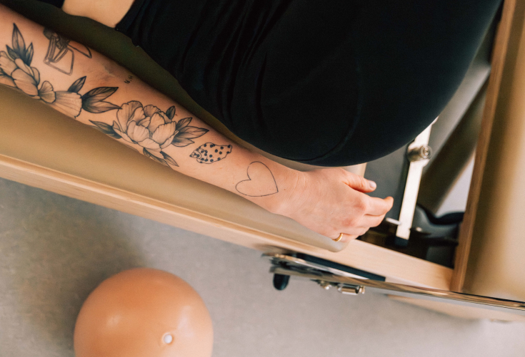 Détail d'une séance Pilates Reformer chez LØFTE Toulouse, bras tatoué sur la machine