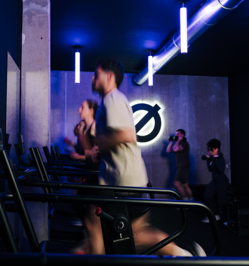 Studio Bootcamp LØFTE Toulouse, course sur tapis auto-entraîné sous néons rouges